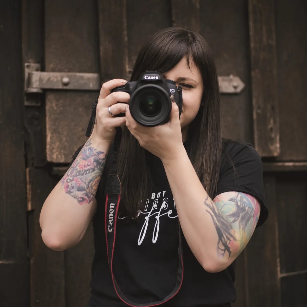 Die Fotografin hinter FOTO FUXX mit ihrer Kamera vor einer dunklen Holztür